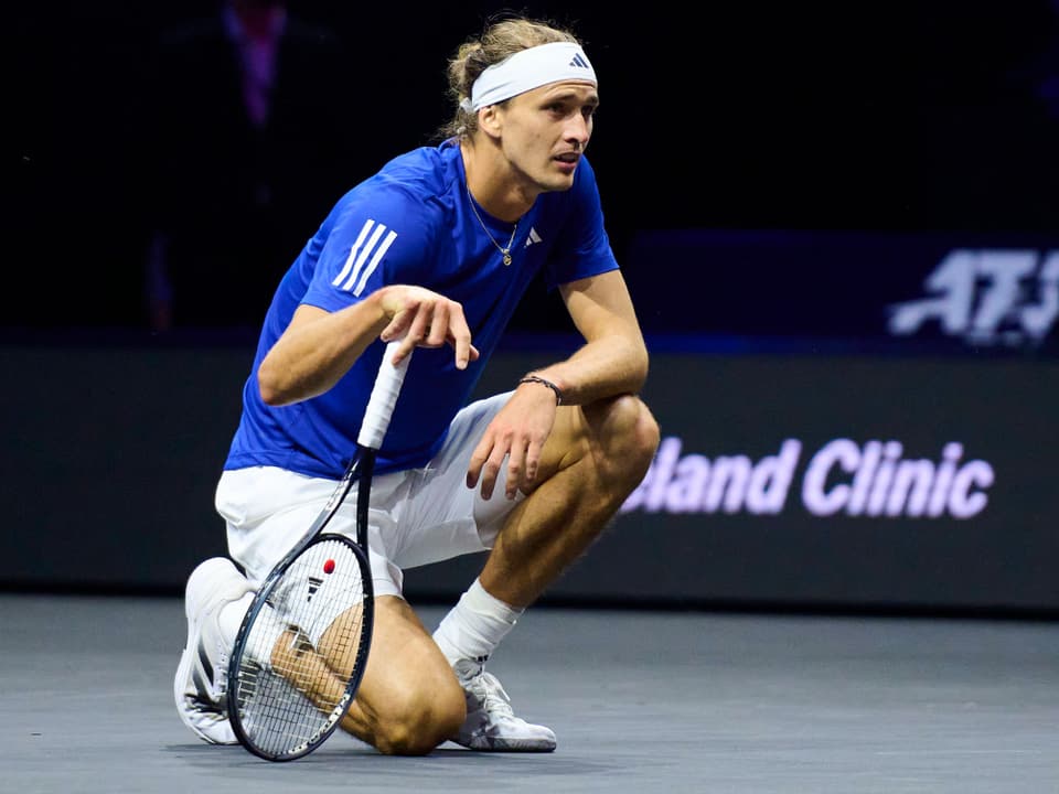 Tennisspieler kniet mit Schläger auf dem Platz.