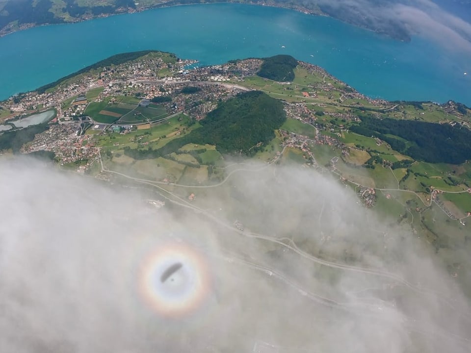 Luftbild eines Sees mit Regenbogen und Wolken.