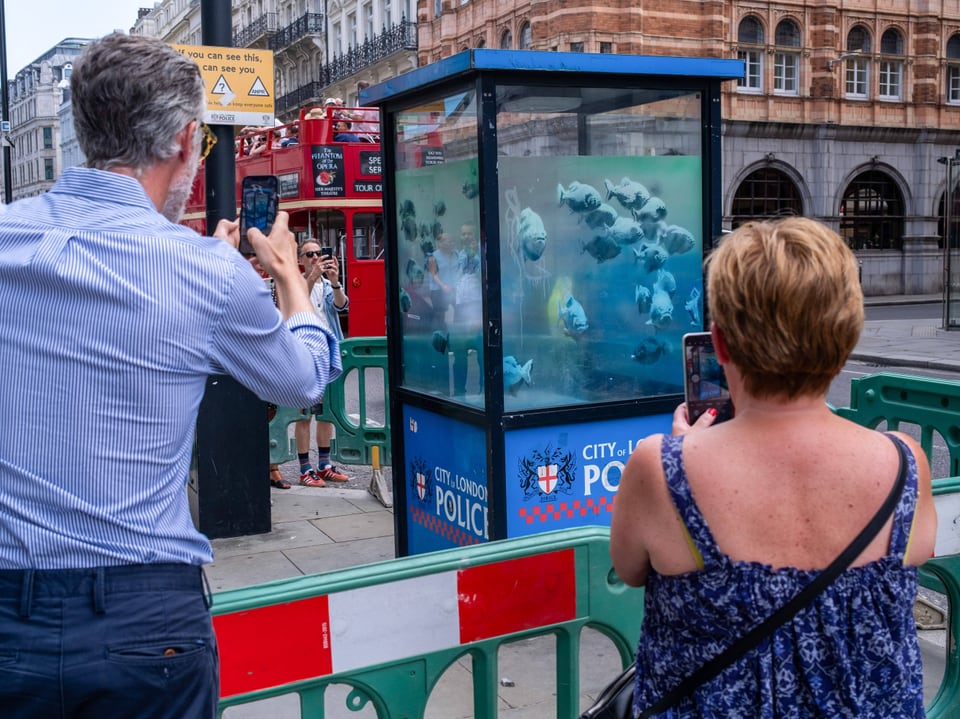 Zwei Personen fotografieren öffentliche Kunstinstallation in London.