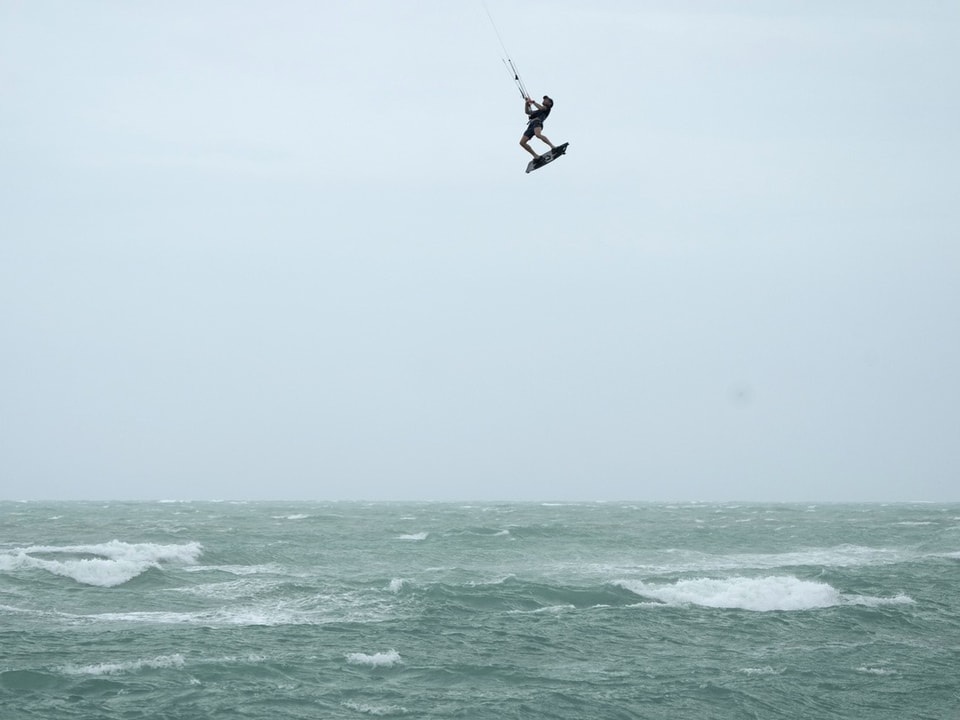 Kitesurfer springt hoch über das Meer.