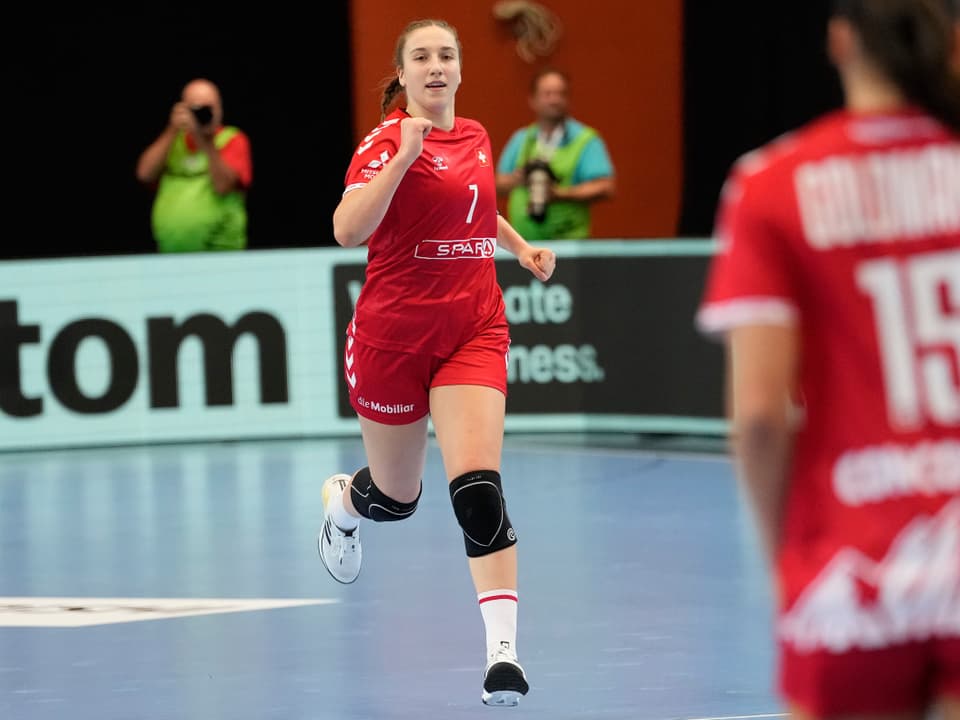 Handballspielerin in rotem Trikot auf dem Spielfeld.