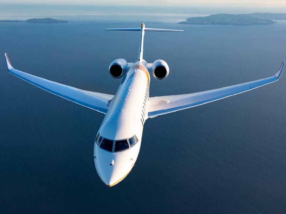 Flugzeug fliegt über das Meer mit Inseln im Hintergrund.