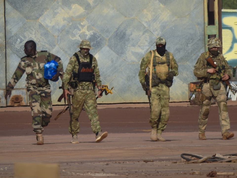 Vier Soldaten in Tarnkleidung gehen nebeneinander.