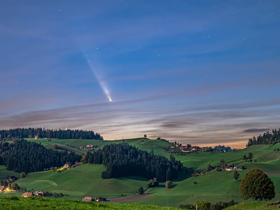 Komet über grüner Hügellandschaft bei Nacht.