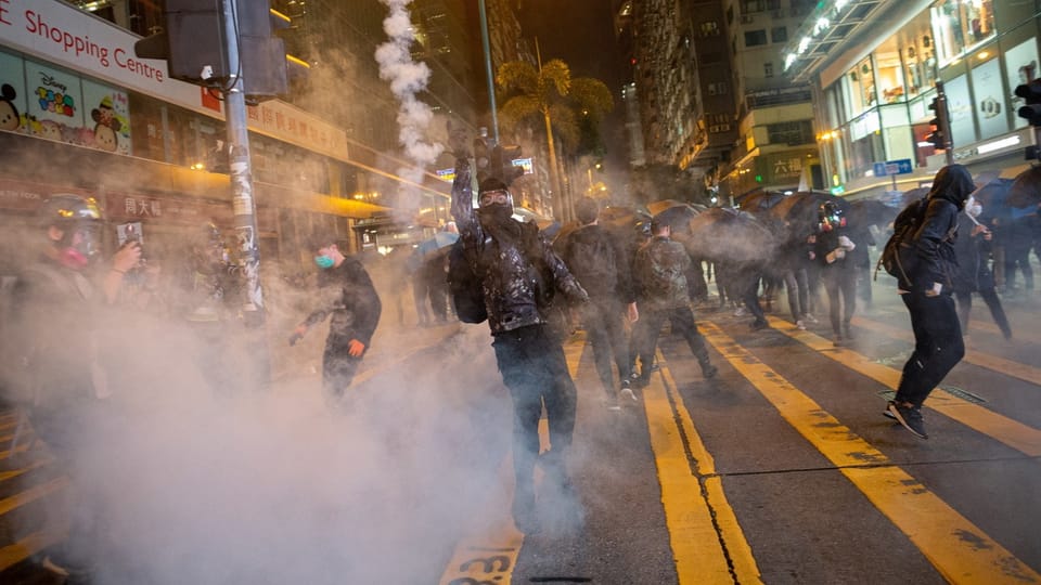 Menschenmenge auf Strasse bei Nacht in Tränengas verwickelt.