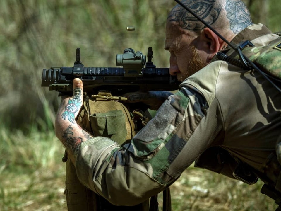 Soldat zielt mit Gewehr im Freien.