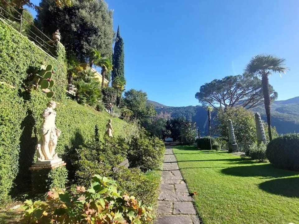 Grüner Garten mit Statuen, der terrassenförmig angelegt ist.