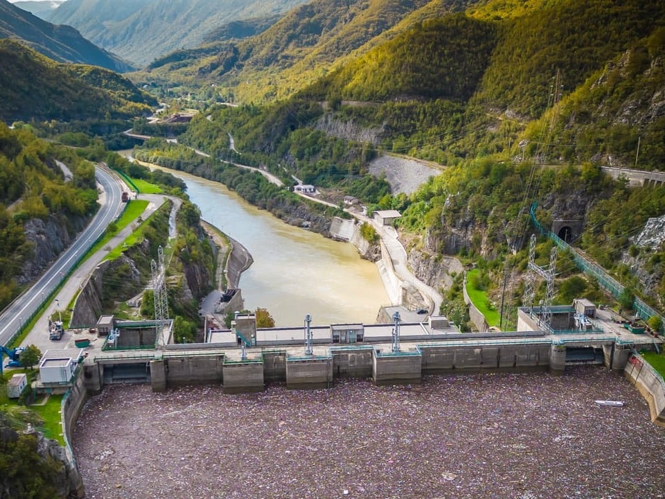 Luftaufnahme eines Staudamms in einer bergigen Landschaft.