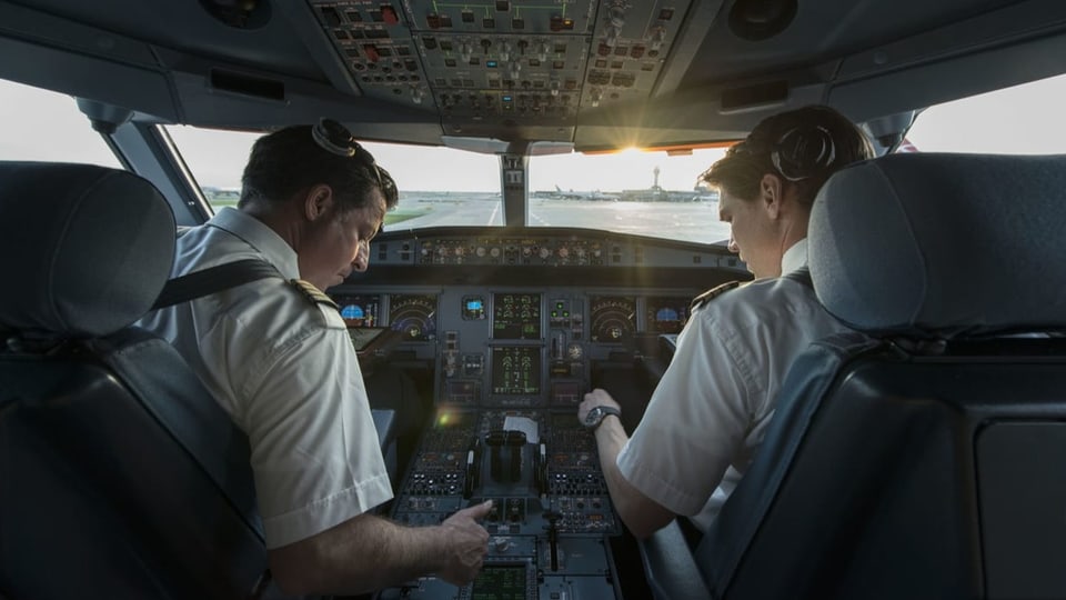 Zewi Piloten schauen auf die Schalter im Cockpit des Flugzeuges.
