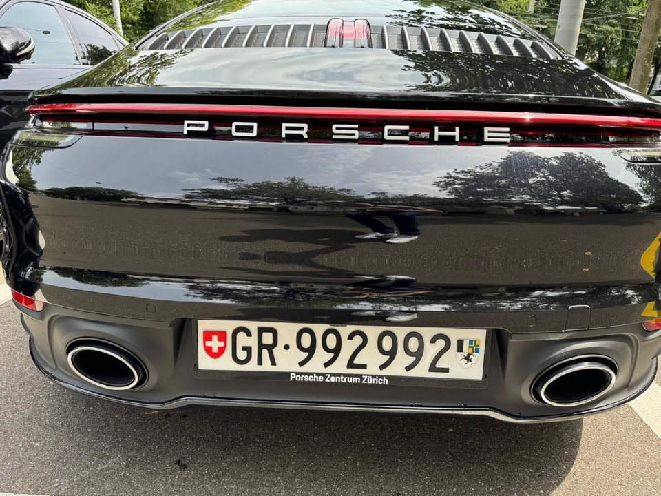 Heckansicht eines schwarzen Porsche mit Schweizer Kennzeichen.