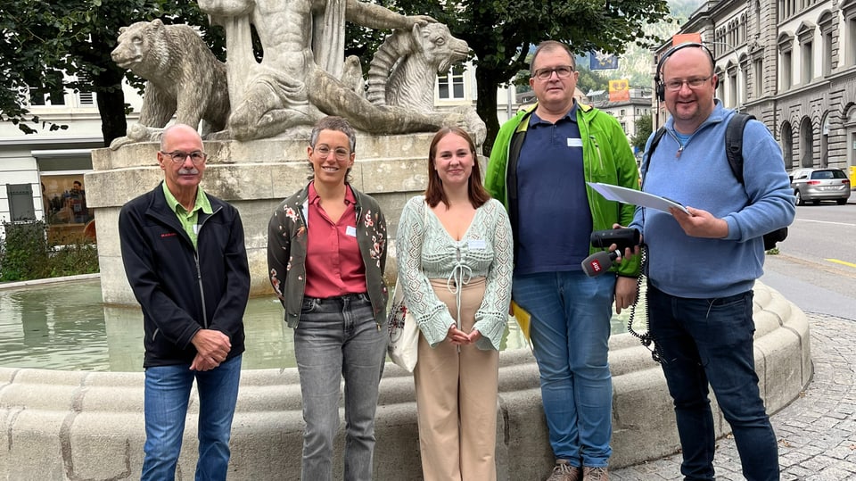 Fünf Menschen vor einem Brunnen.