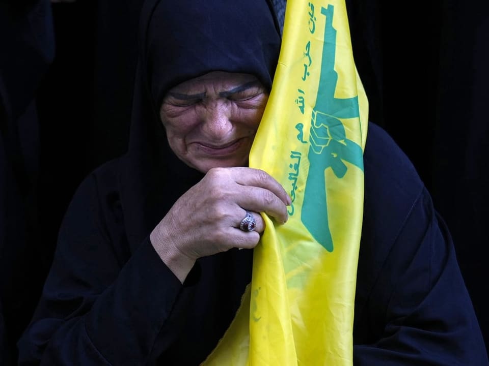 Frau weint mit umgehängter Hisbollah-Flagge 