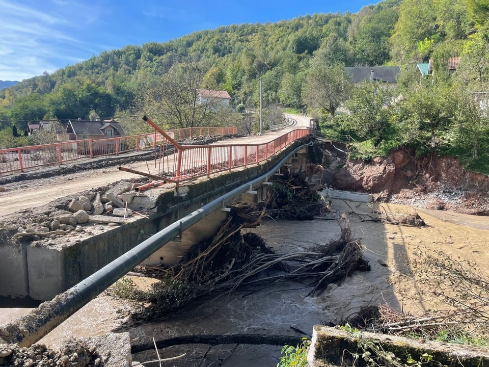 Teilweise eingestürzte Brücke über schlammigen Fluss.