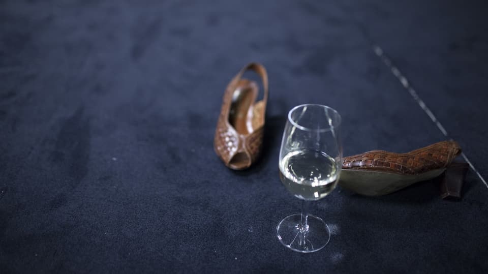 Sandalen und Glas Weisswein auf Teppichboden