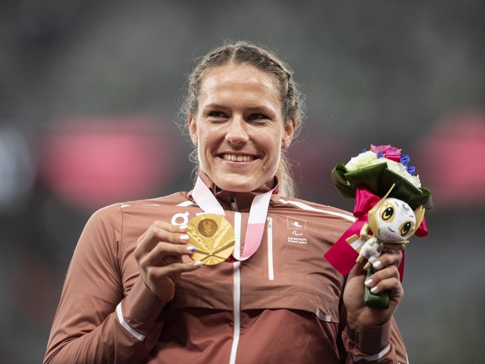 Sportlerin hält Medaille und Blumenstrauss