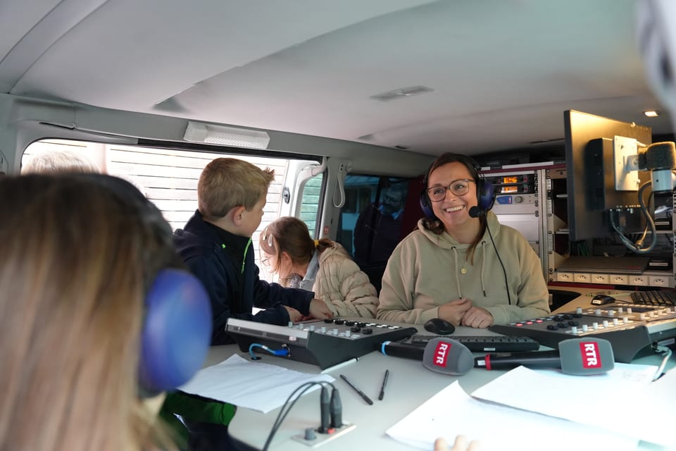 Kinder und eine Frau mit Kopfhörern im Radiostudio im Van.