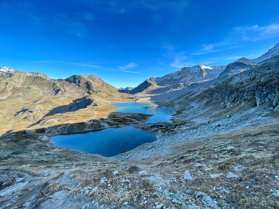 Bergsee in alpiner Landschaft unter blauem Himmel.