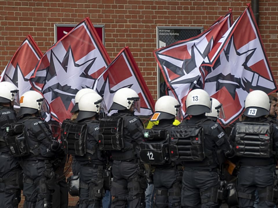 Polizei, im Hintergrund Fahnen der Pnos