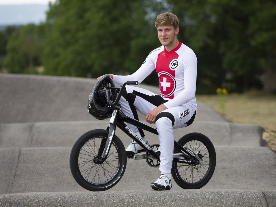 Radfahrer auf BMX-Rad in weisser Rennkleidung sitzt auf einer Strecke.