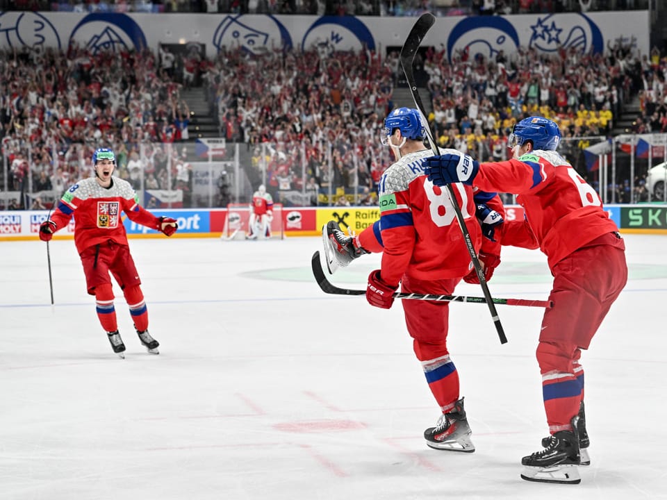 Eishockeyspieler in roten Trikots feiern ein Tor.