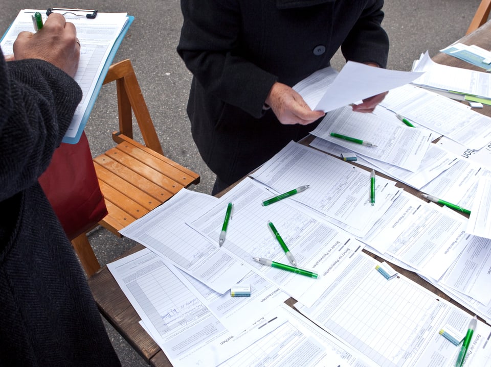 Unterschriftenzettel liegen auf einem Tisch bereit zum Unterzeichnen.