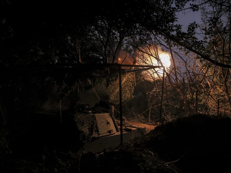 Es ist Nacht: Ein Maschinengewehr schiesst in die Dunkelheit hinein, umarmt von Bäumen und Geäst.