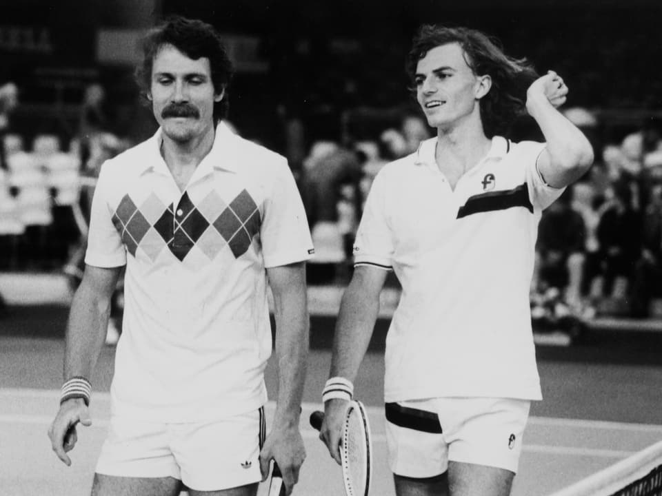 Two tennis players on the court in the 1970s, black and white shot.