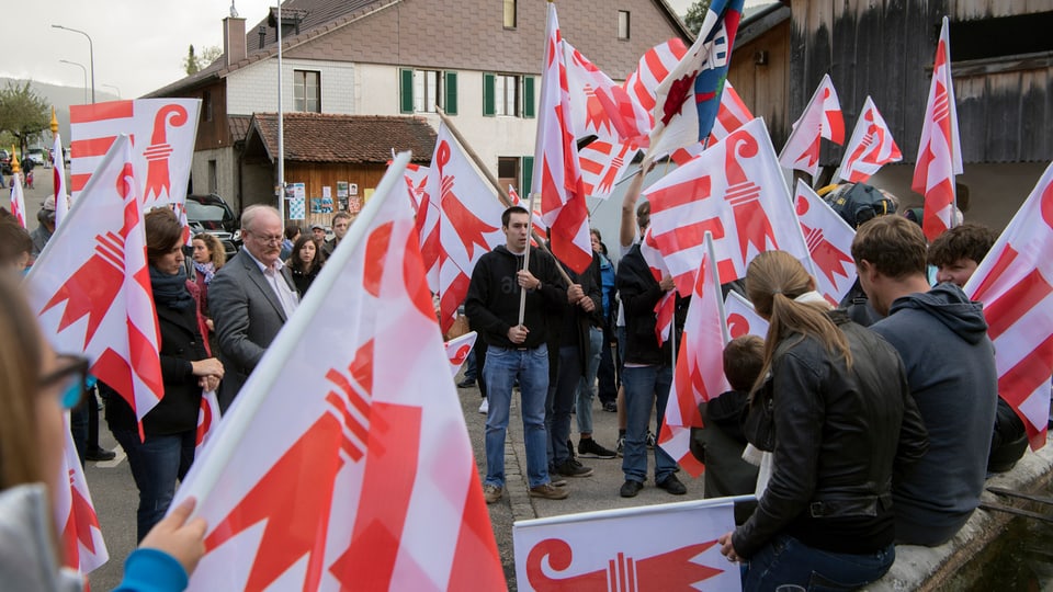 Menschen mit Jurafahnen stehen beeinander.