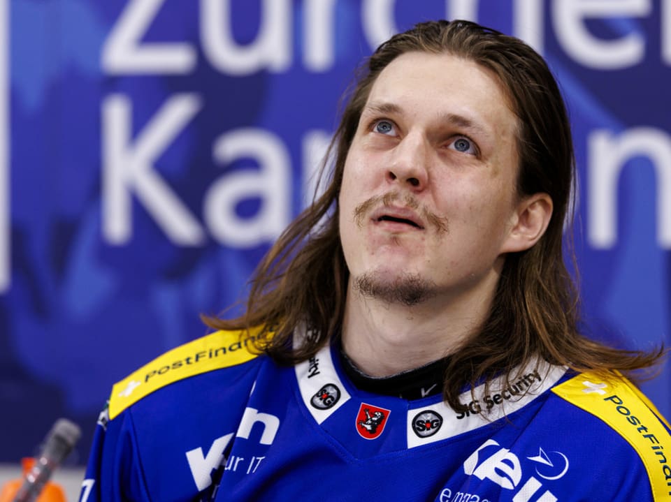 Eishockeyspieler im blauen Trikot auf der Bank.