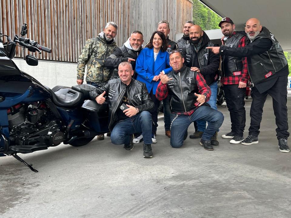 Ein Gruppenfoto neben einem Motorrad. Eine Gruppe von Bikern, gekleidet in schwarzem Leder, posiert mit Mona.