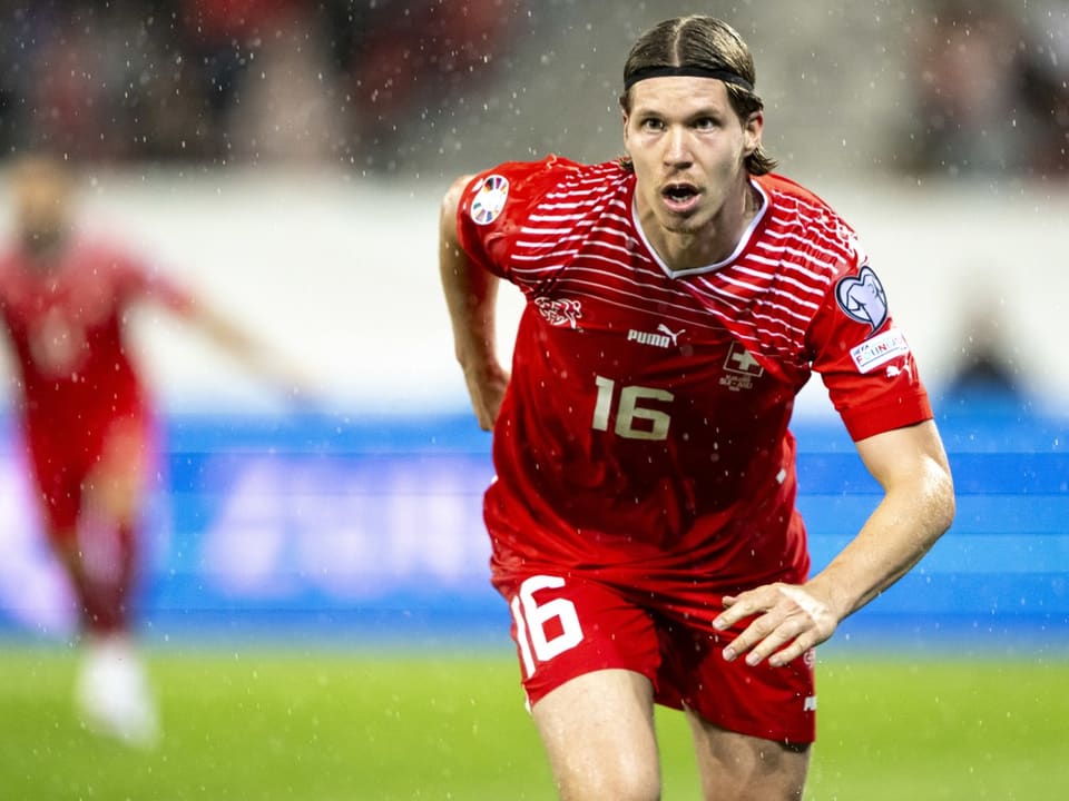 Schweizer Fussballspieler im roten Trikot bei Regen.