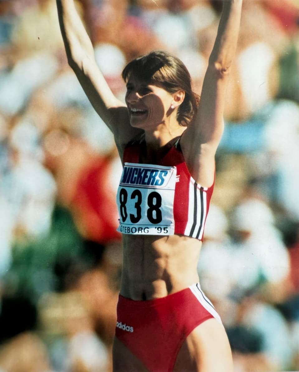 Sportlerin in roter Sportkleidung hält die Arme hoch, trägt die Startnummer 838.