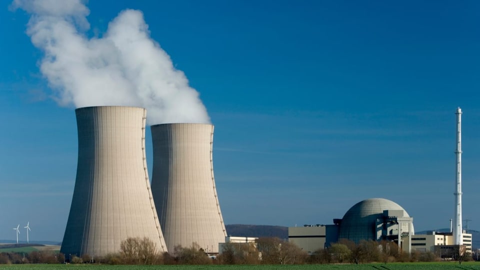 Ein Atomkraftwerk in der Näge zweier Windräder.