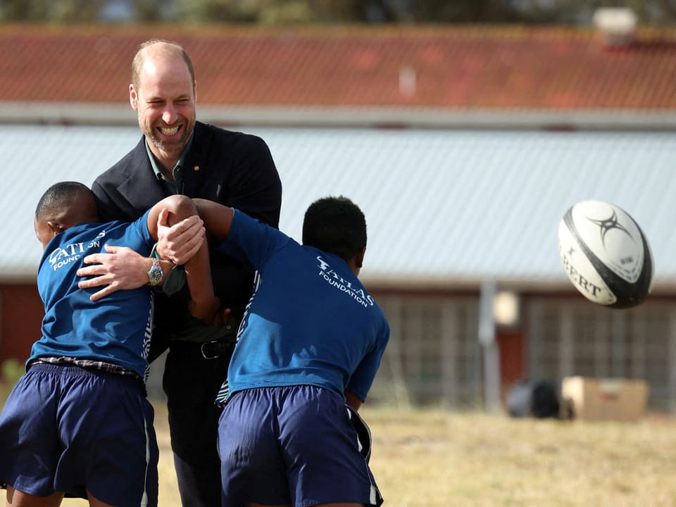 Erwachsener trainiert zwei Jungen im Rugbyspiel.