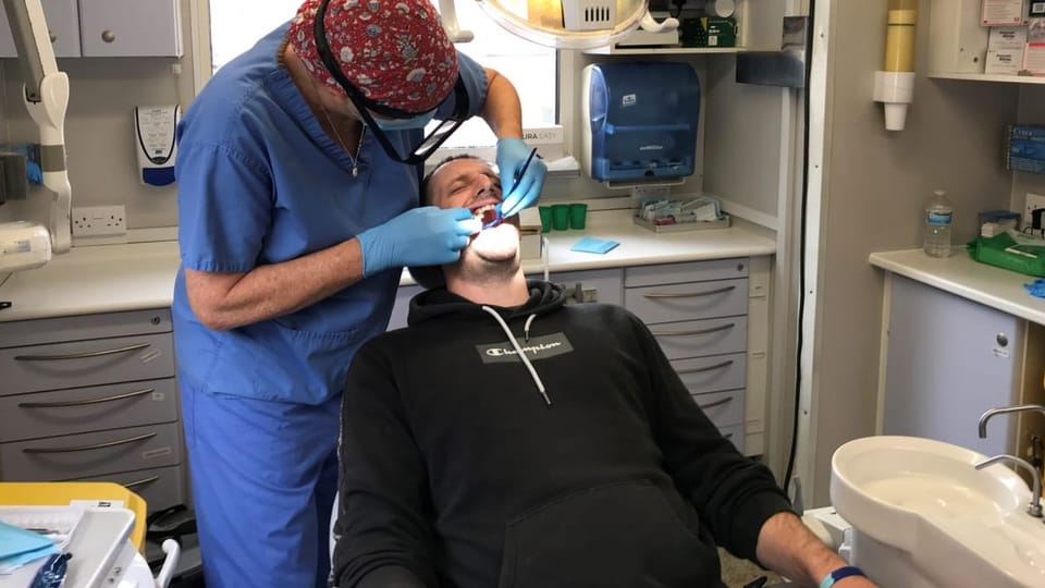 Edwards sitzt im Stuhl, während eine Zahnpflege-Fachperson in blau gekleidet in seinem Mund herumwerkt.