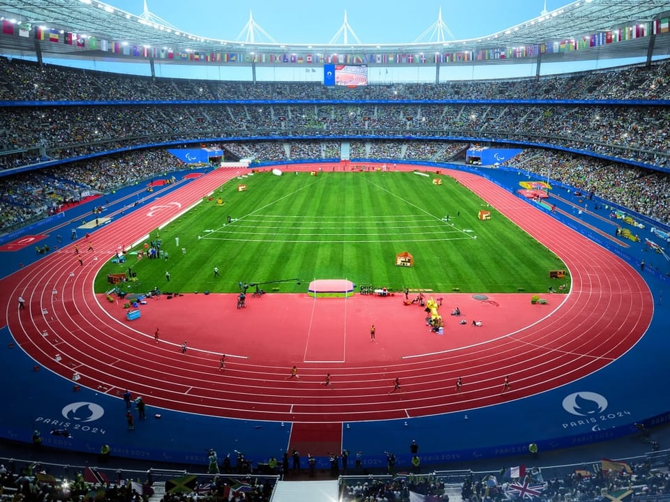 Olympiastadion mit Laufbahn und Rasenplatz, voll besetzt.