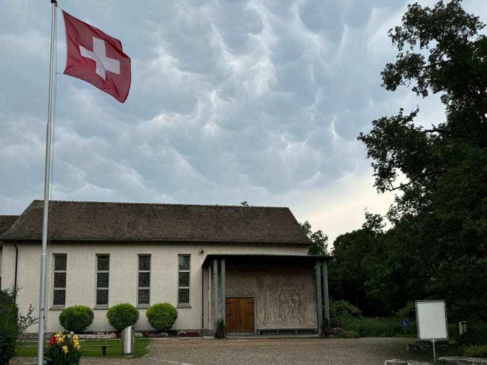 Gebäude mit Schweizer Flagge und bedecktem Himmel.