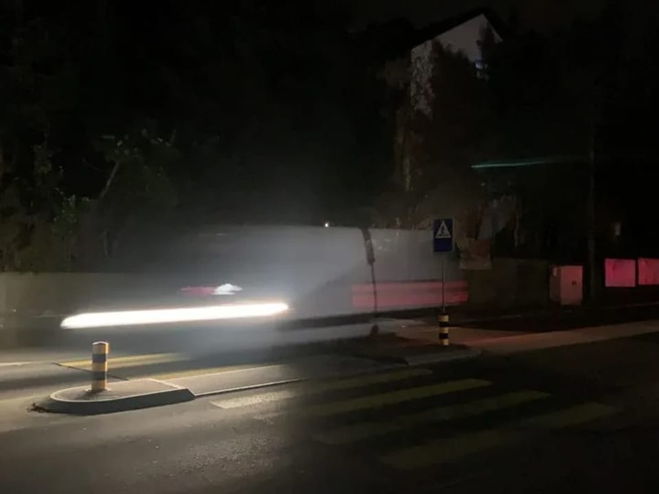 Eine Strasse bei Nacht, ein Auto fährt an einem Fussgängertstreifen vorbei.