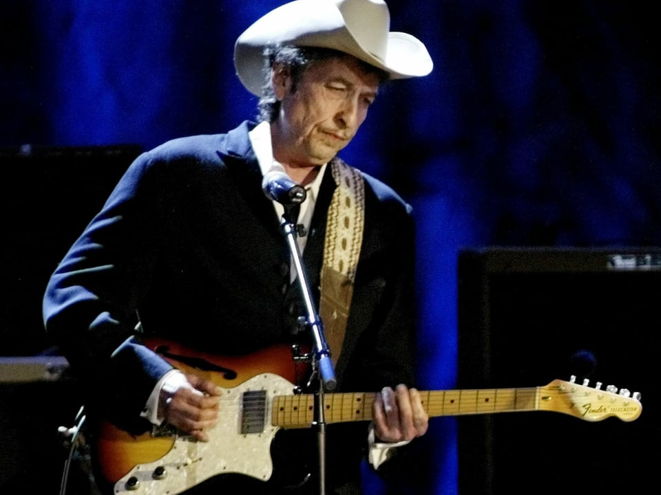 Bob Dylan spielt Gitarre auf einer Bühne.