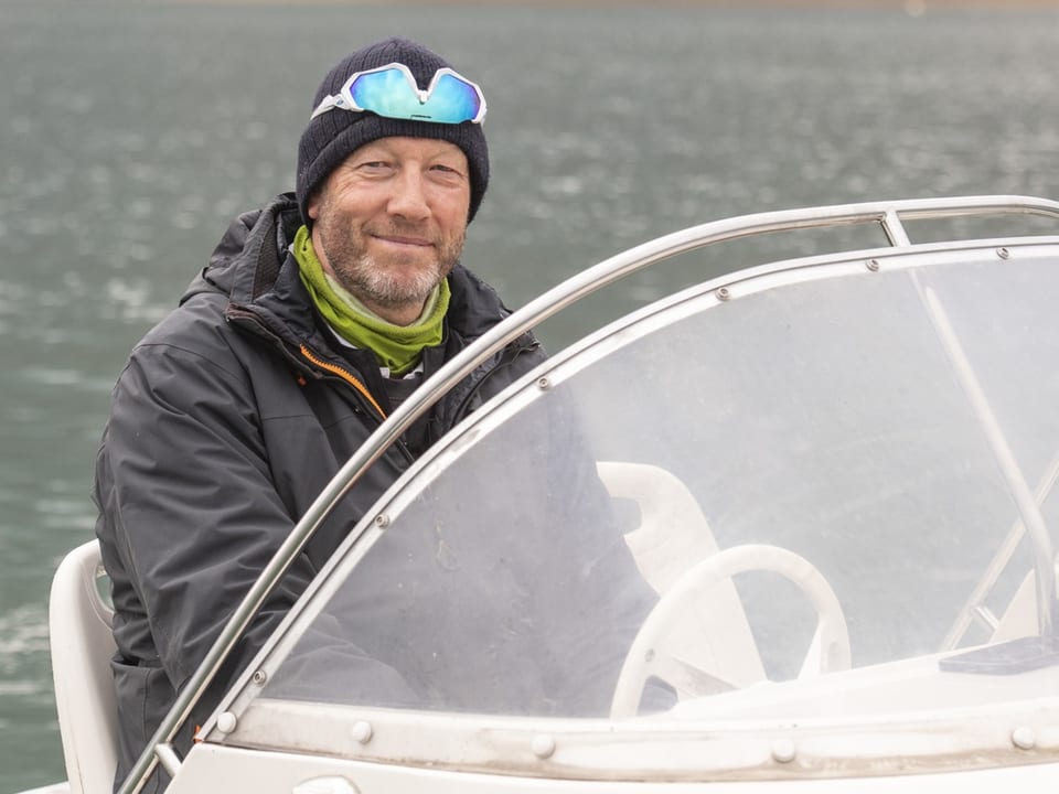 Mann mit Mütze im Motorboot auf dem Wasser.