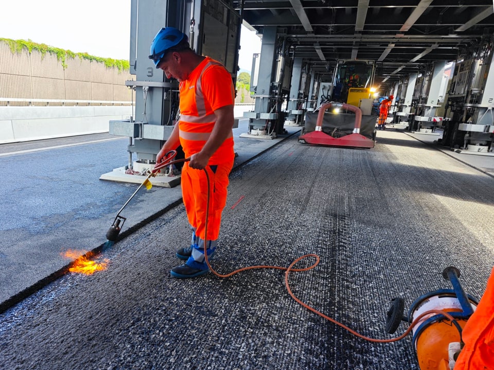 Bauarbeiter mit Flammenwerfer auf Autobahnbaustelle.