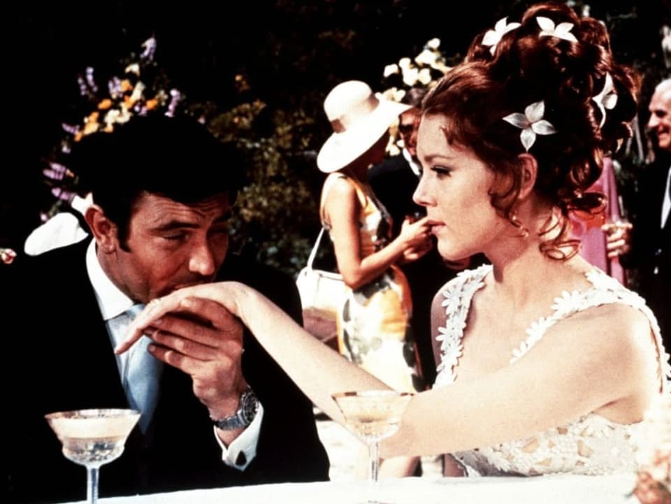 Ein Mann im Smoking küsst mit geschlossenen Augen eine Frau im Brautkleid.