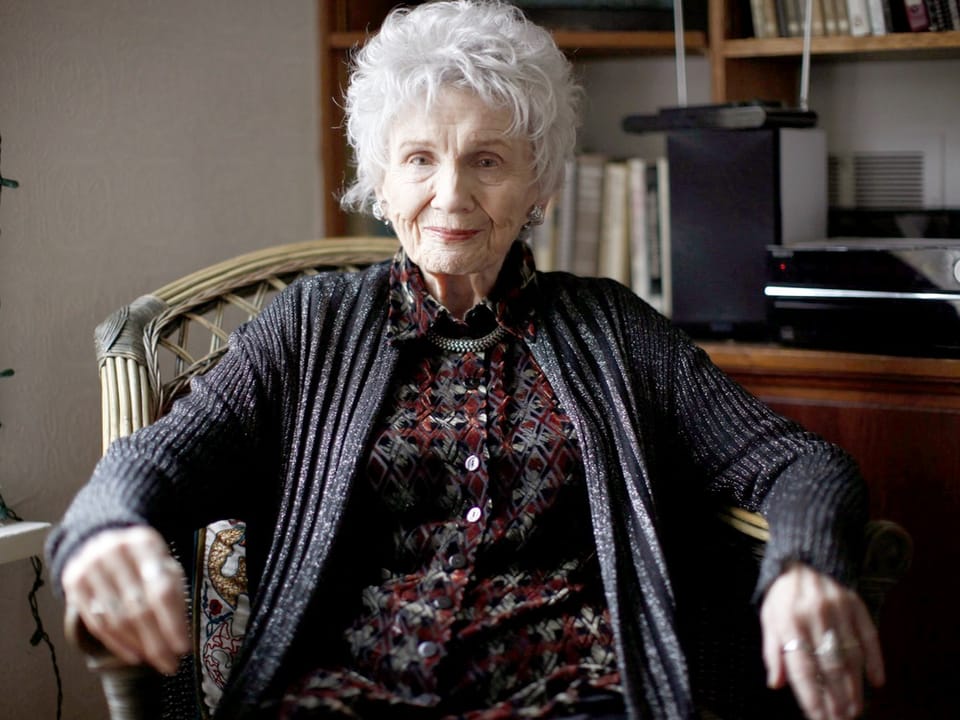 Ältere Frau mit grauem Haar in einem Sessel sitzend in einem Wohnzimmer.