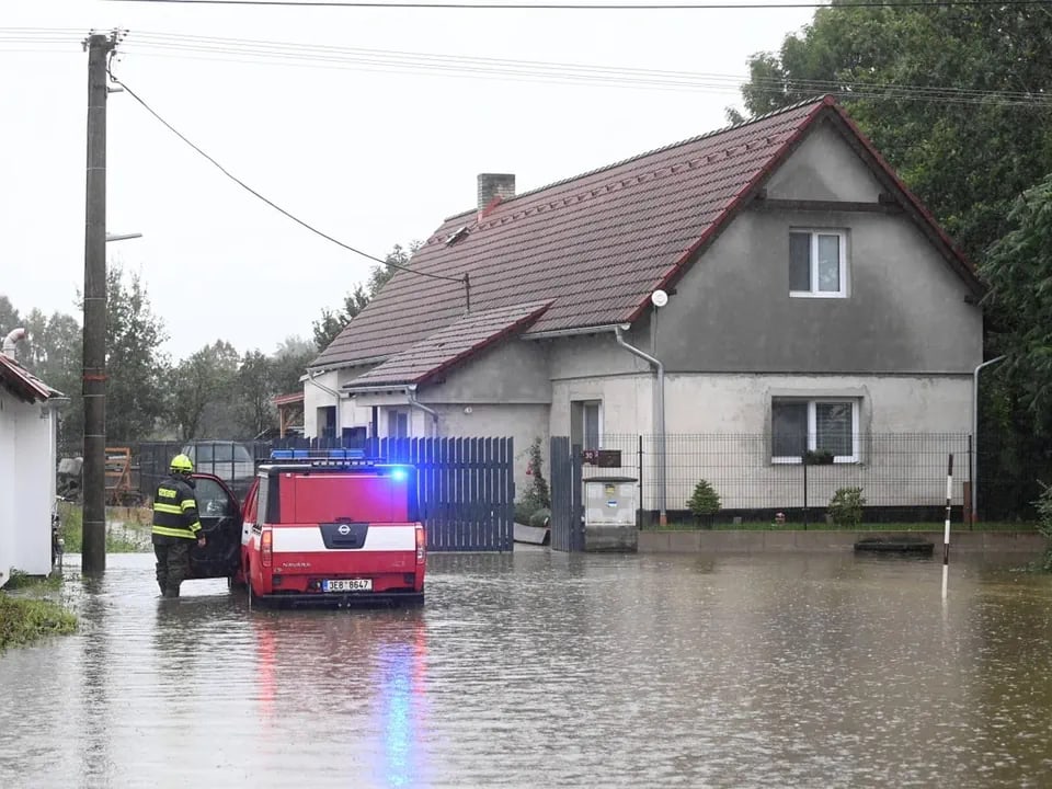 Feuerwehr bei Hochwasser vor einem Haus.