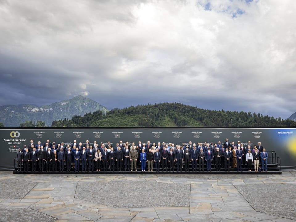 Gruppenfoto von Personen vor einer Berglandschaft bei einer Friedensgipfel-Veranstaltung.