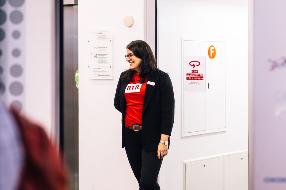 Frau im Büro mit rotem T-Shirt und schwarzer Jacke.