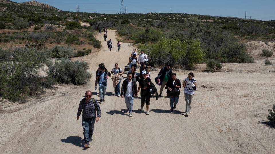 Eine Gruppe von Immigranten auf einem Wüstenpfad.