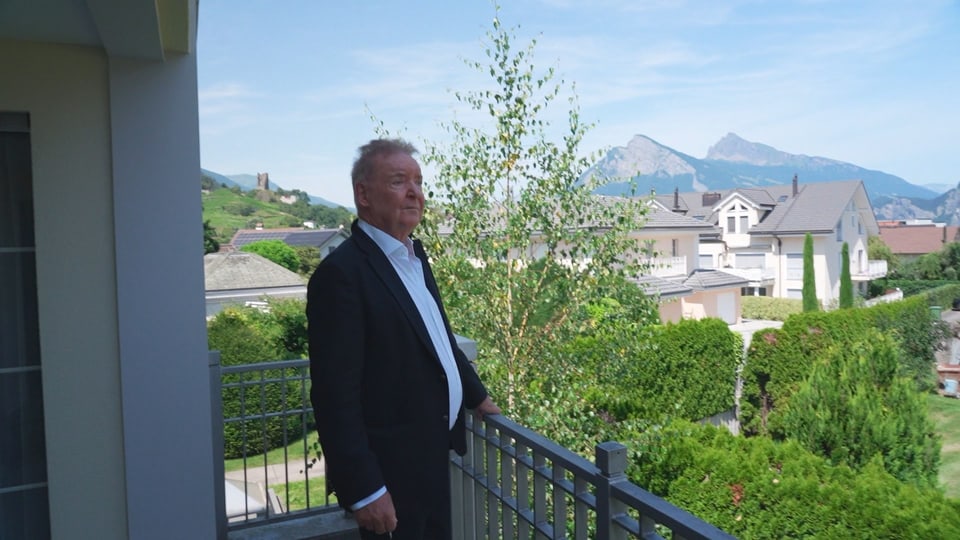 Mann steht auf Balkon mit Bergblick.