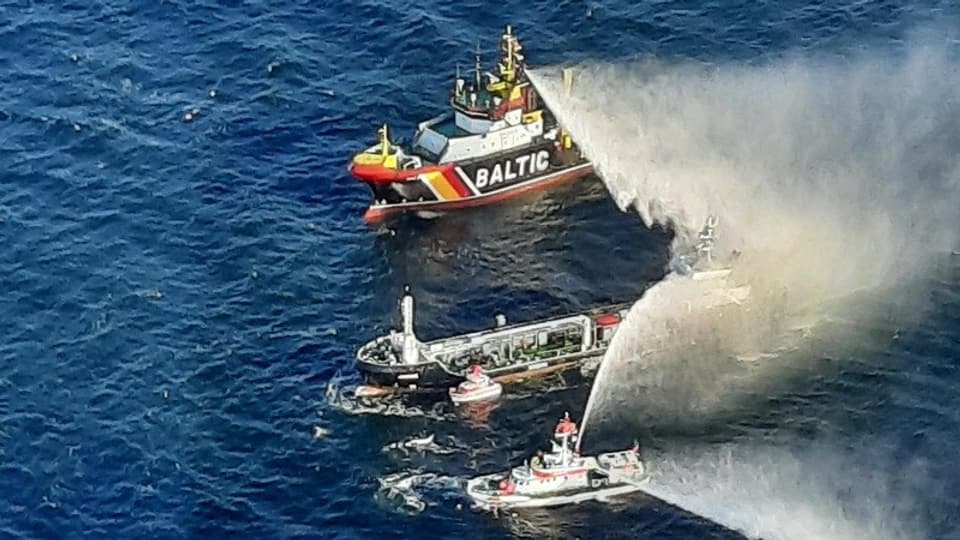 Feuerlöschboote löschen Feuer auf dem Meer.