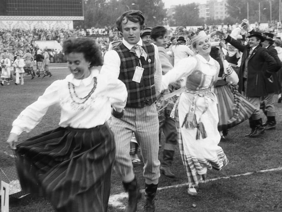 Menschen tanzen in traditioneller Kleidung auf Festival.
